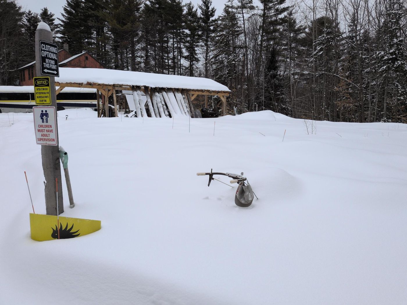 camp sign post and equipment buried in deep winter snow at Bartertowne, Canaan New Hampshire